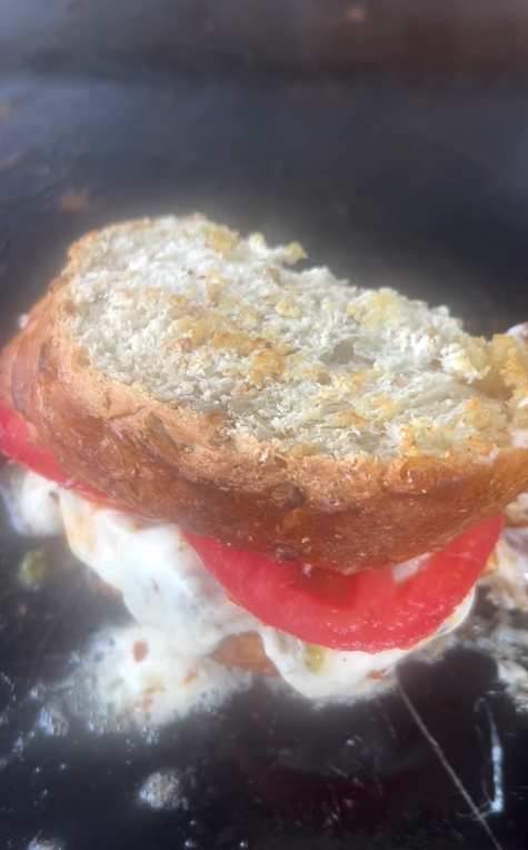 Grilled cheese with fresh tomato and herbed cheese melting on the griddle